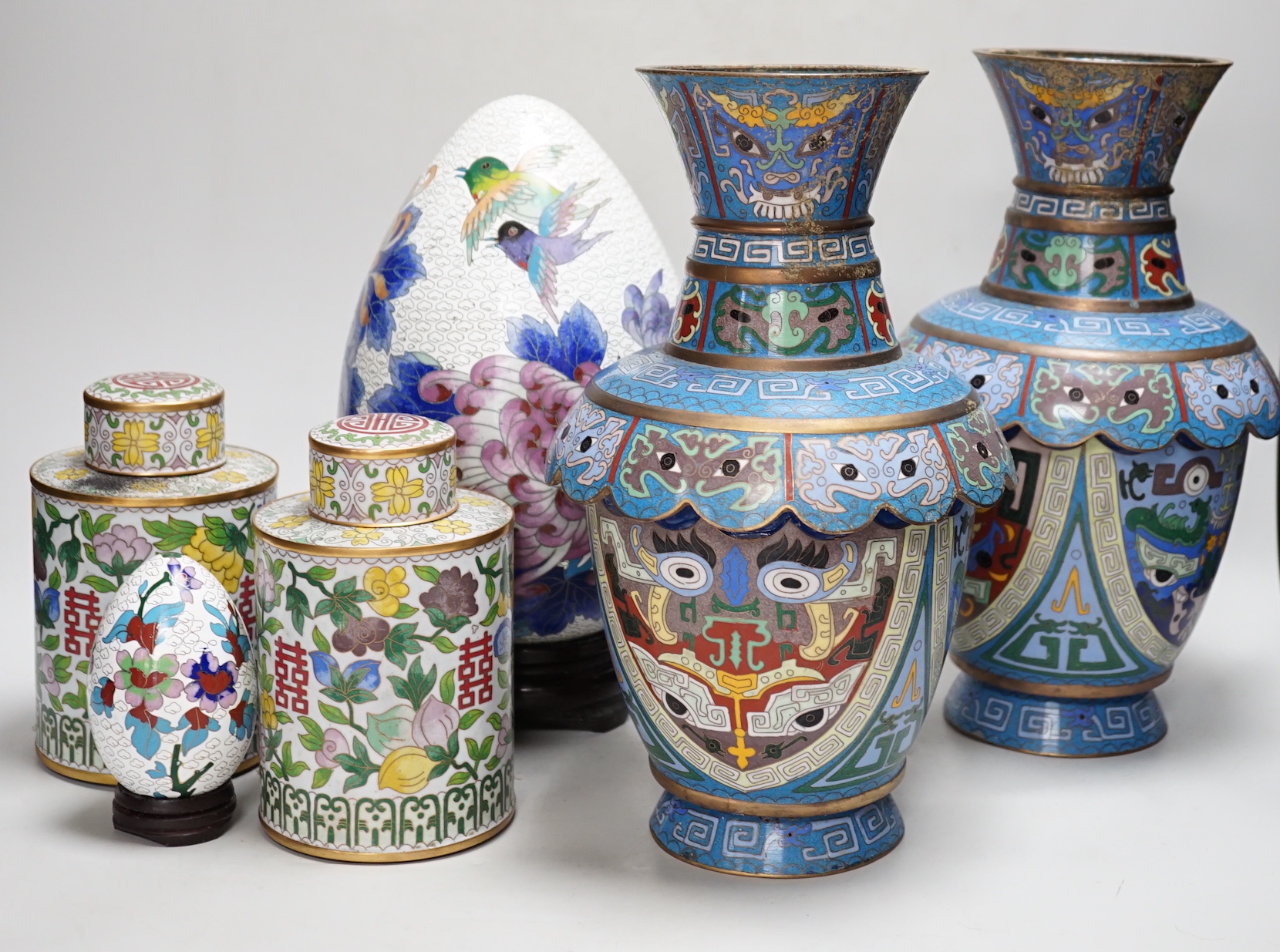 A pair of Chinese cloisonné enamel vases, a pair of canisters and covers, a large egg on stand and a small egg on stand